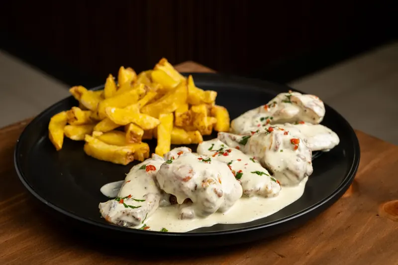 Alitas acevichadas con papas fritas